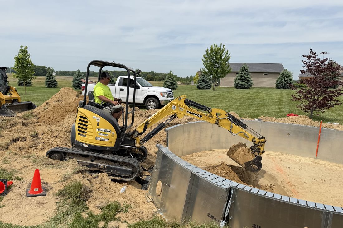 Excavator shaping the pool site with the Brighton Pools truck on site